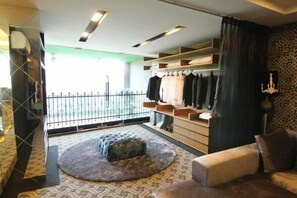 Een moderne kamer met balkon, een rond poef, een bank en een kledingrek.