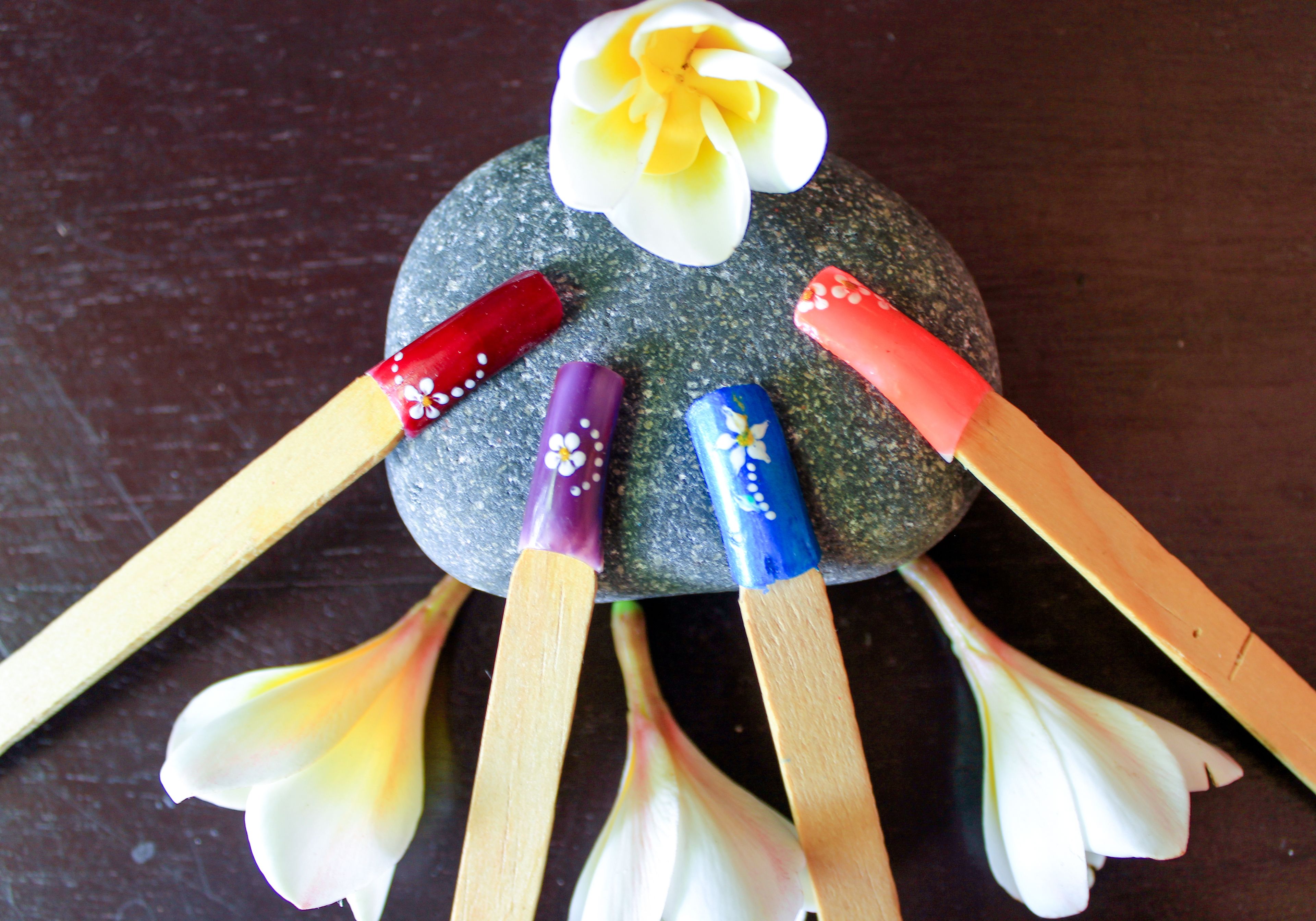 A stone with a flower and four sticks with painted ends.