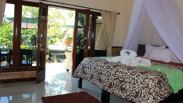 A bedroom with a bed, a canopy, and a view of the outside. - Man's Cottages and Spa (Pemuteran)