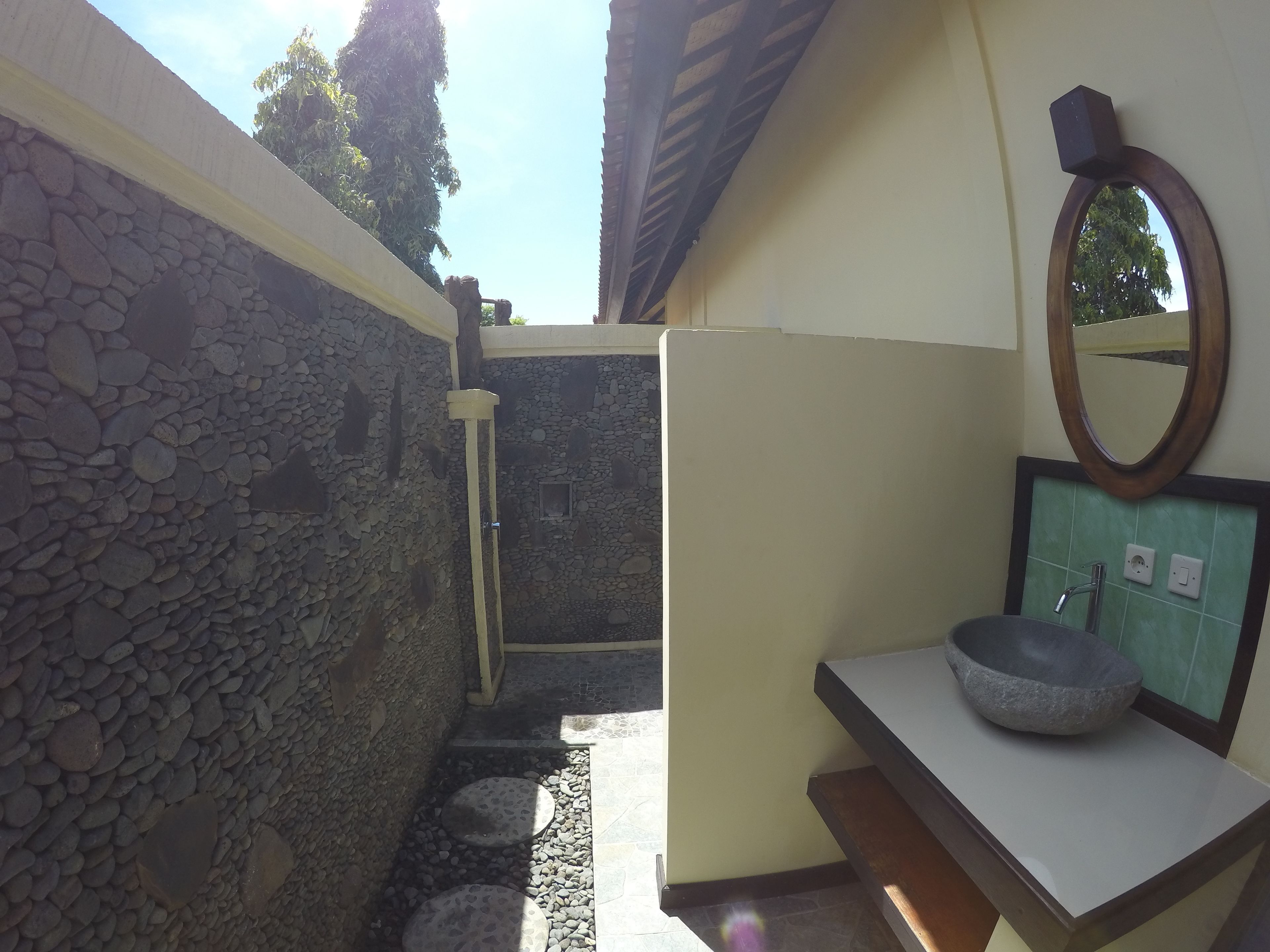 Un baño con pared de piedra, un lavabo de piedra y un espejo en la pared.