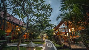 A pathway leading to a building with a tiled roof, surrounded by lush greenery and a well-maintained garden. - Man's Cottages and Spa (Pemuteran)