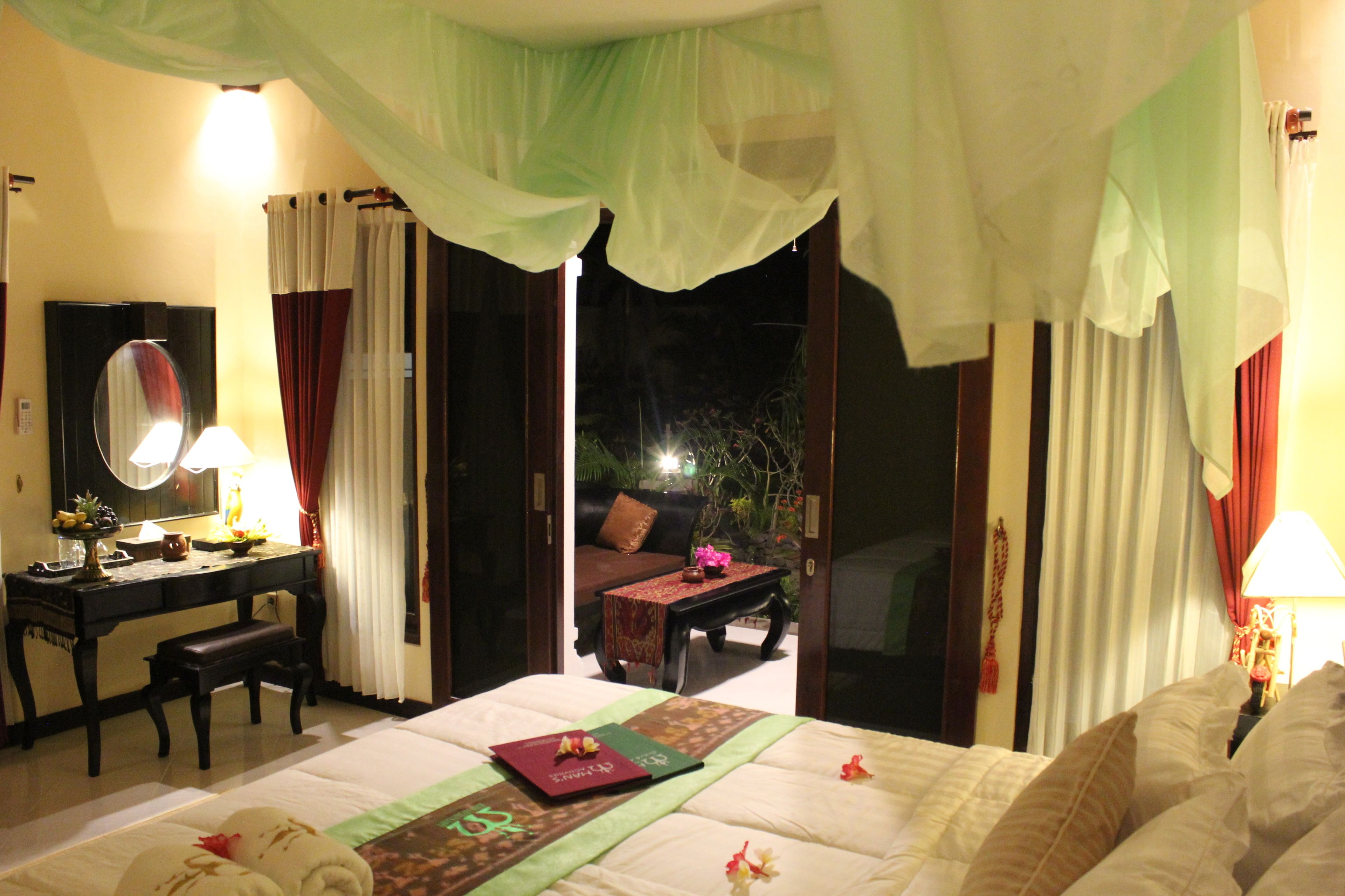 Habitación de hotel con cama, escritorio, silla, espejo y vistas al exterior.