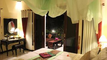 Habitación de hotel con cama, escritorio, silla, espejo y vistas al exterior.
