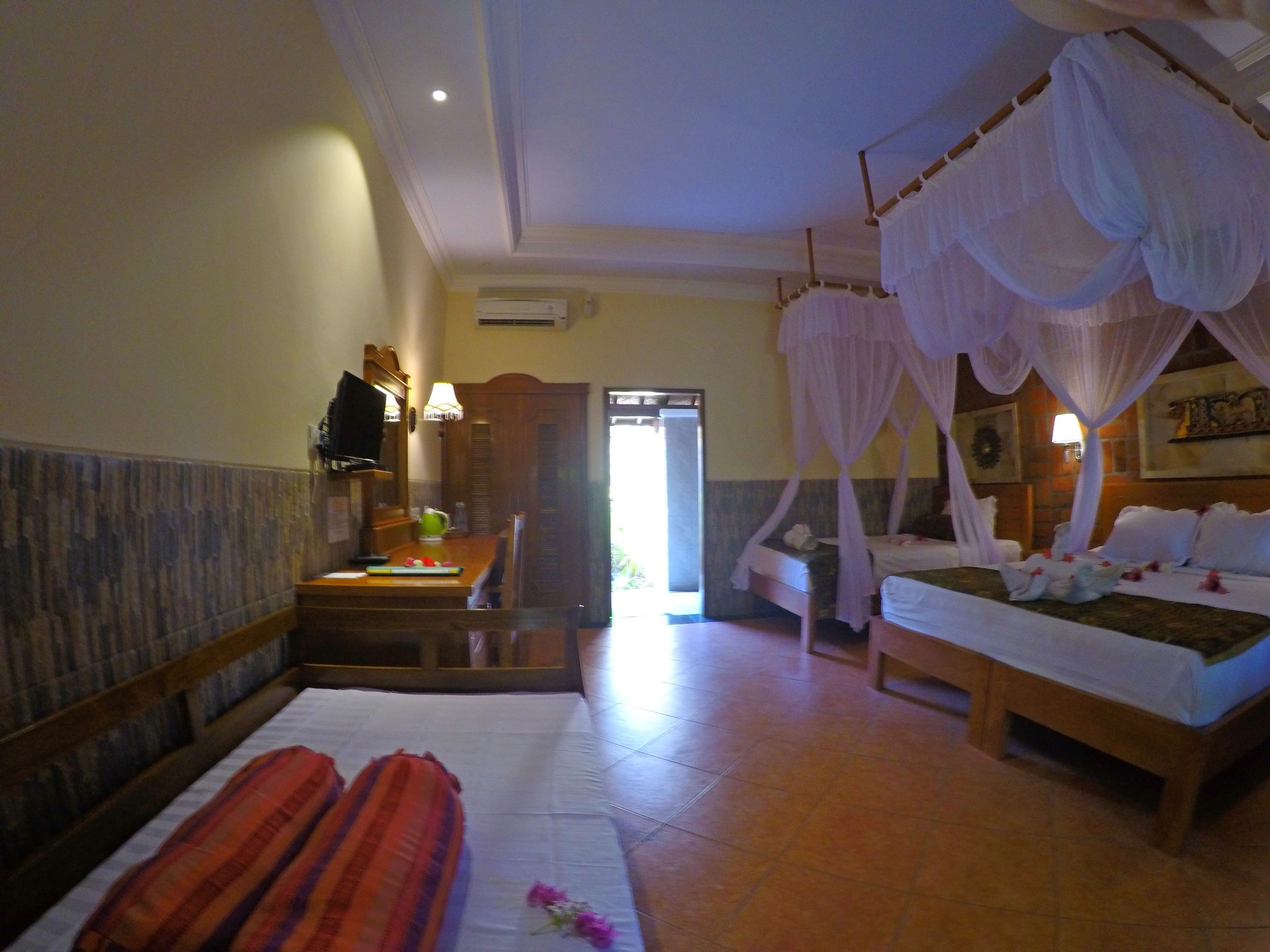 A hotel room with a bed, a bedside table, a mirror, and a window.