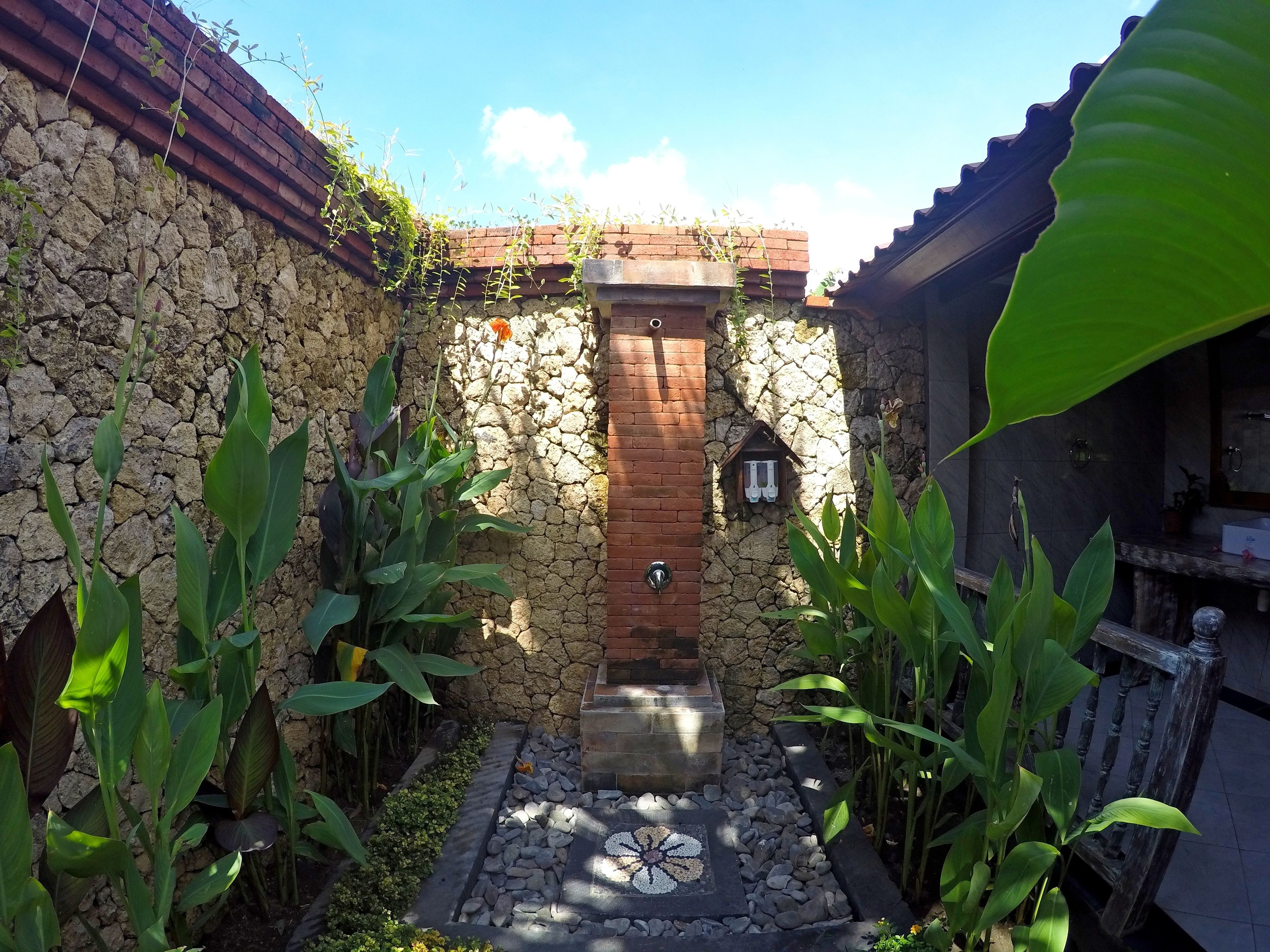 Une cour avec un mur en pierre, une porte en bois et un sol carrelé.