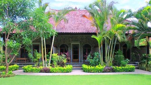A traditional building with a tiled roof, surrounded by lush greenery and a well-maintained lawn. - Man's Cottages and Spa (Pemuteran)