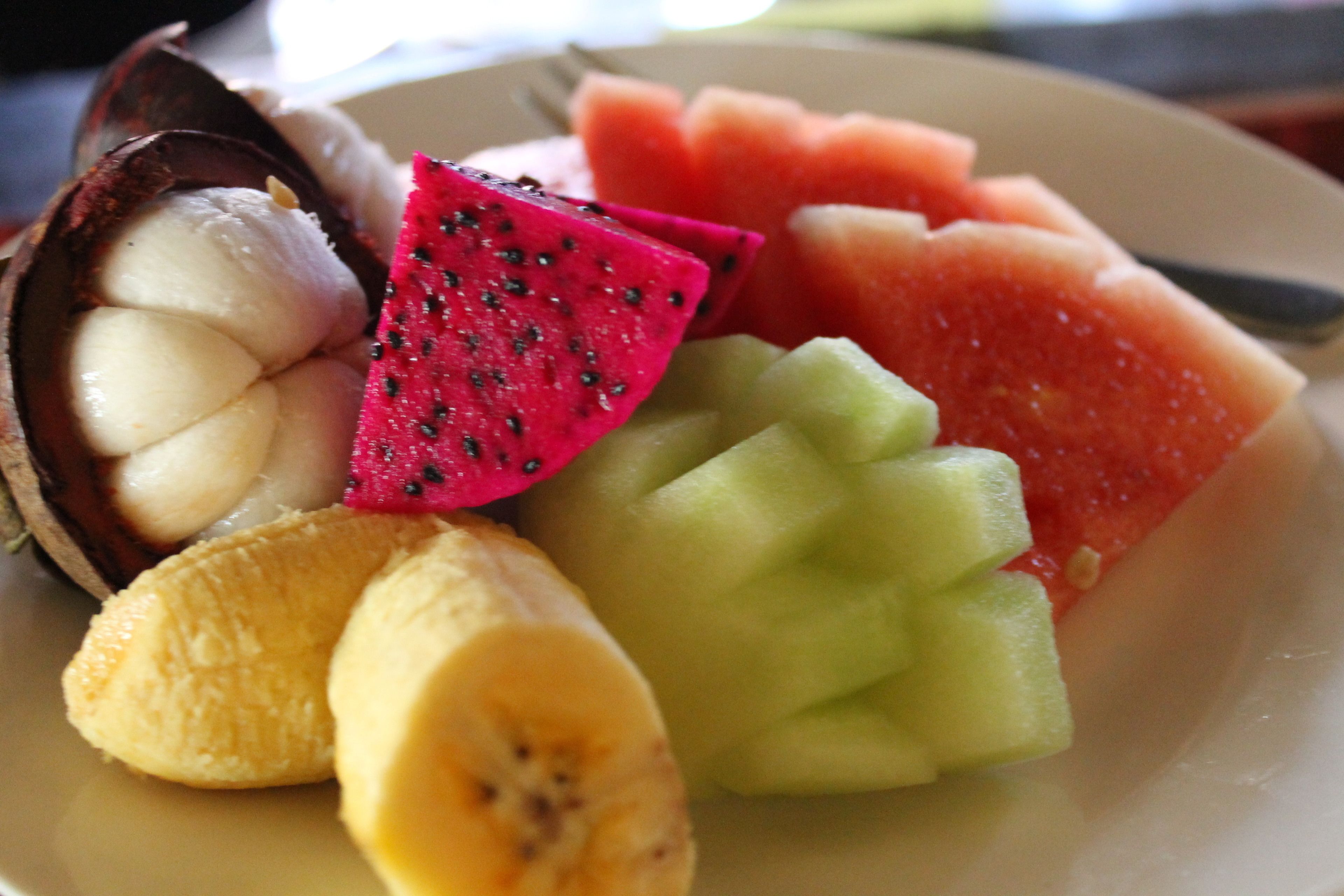 Un plato con pitahaya, sandía, melón cantalupo y plátanos.
