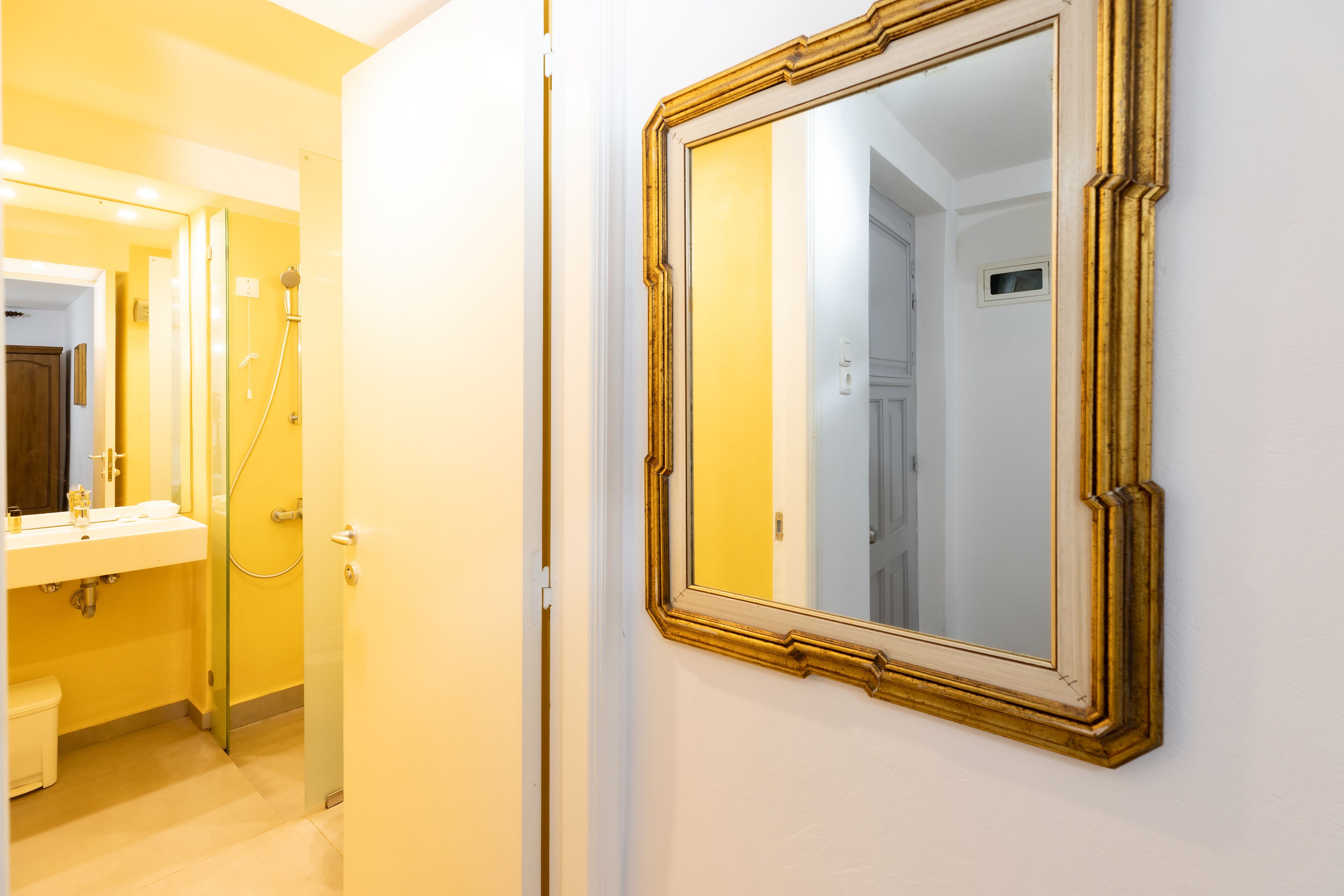 Un baño con lavamanos blanco, espejo y cabina de ducha de vidrio.