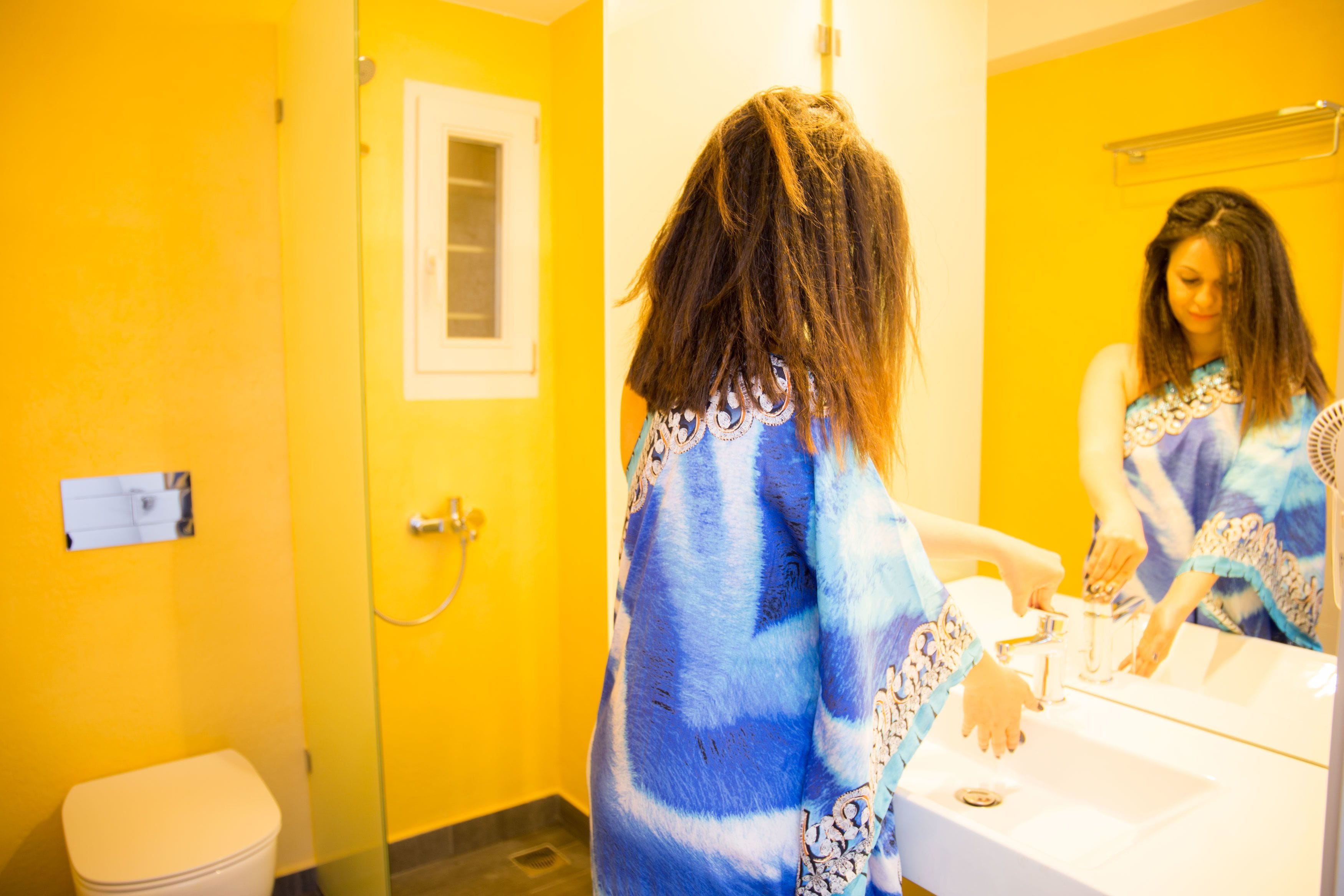 A bathroom with a yellow wall, a white toilet, and a sink.