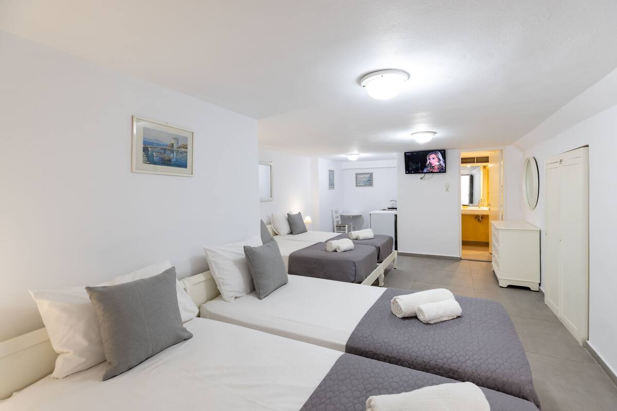 Une chambre d’hôtel avec deux lits, une télévision, un bureau et une salle de bain visible à travers une porte ouverte.