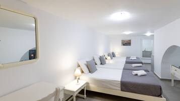 Ett hotellrum med en stor säng, ett skrivbord, en stol, en spegel och ett badrum som syns genom en valvöppning.
