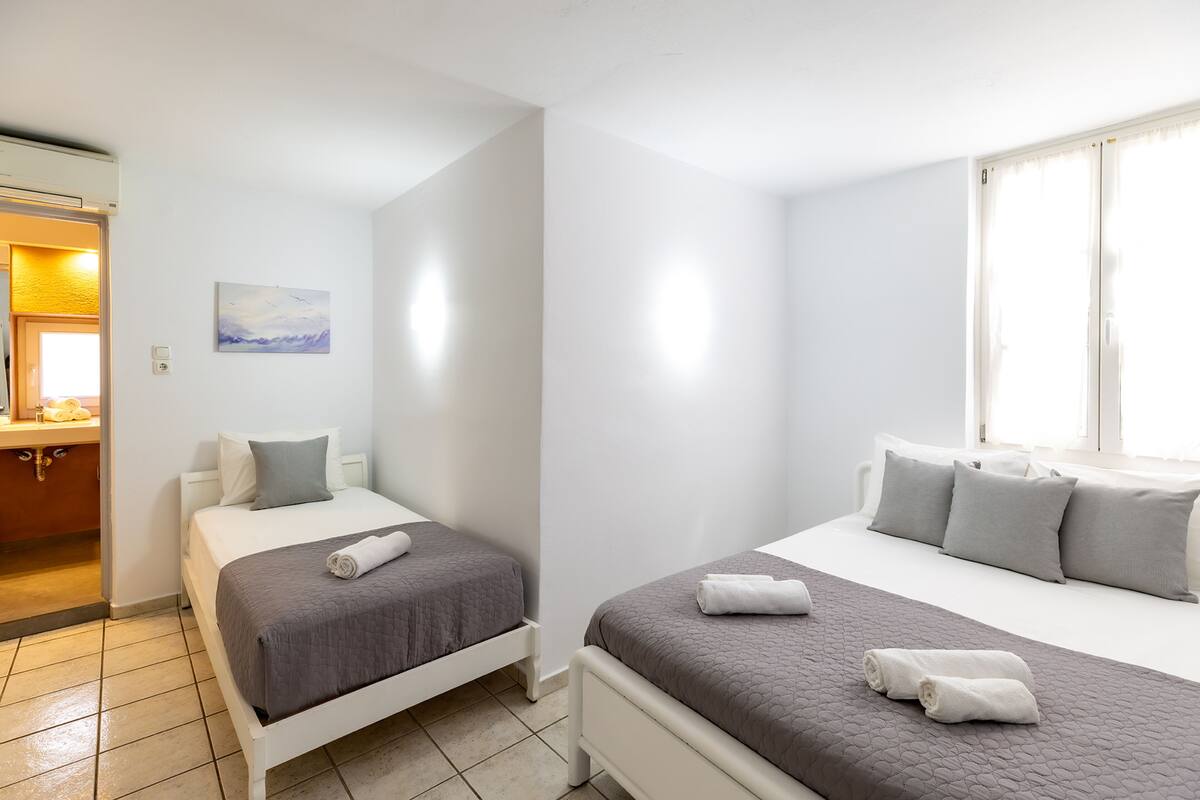 Une chambre d’hôtel avec deux lits, un tableau au mur et une fenêtre avec des rideaux.