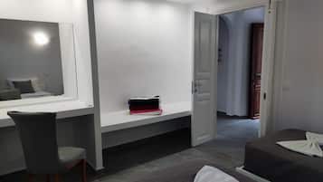 Una habitación de hotel moderna con un espejo grande, un escritorio, una silla, una cama con colcha y un armario.
