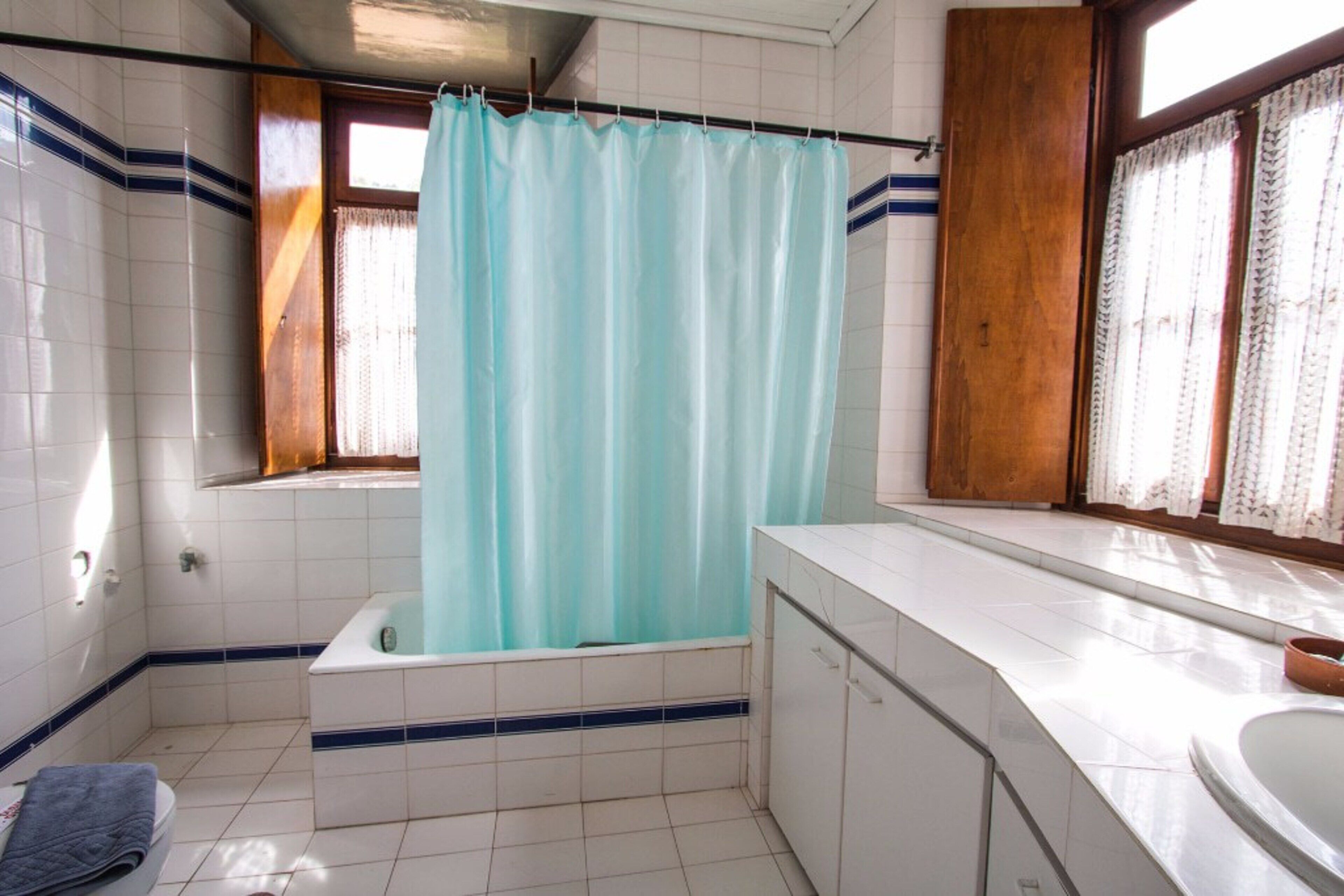 A bathroom with a bathtub, a sink, and a window with curtains.
