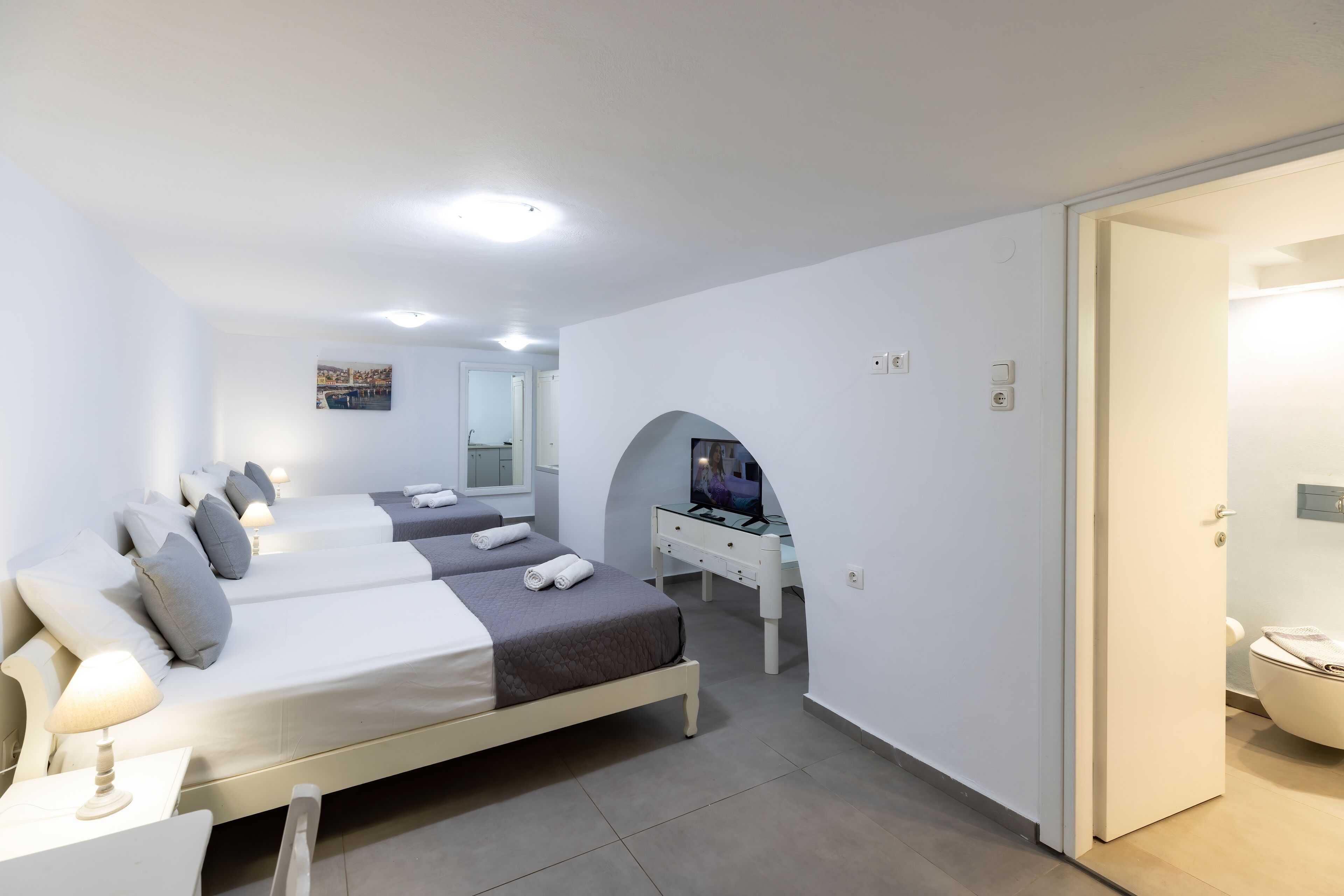 A modern hotel room with two beds, a desk, and a TV.