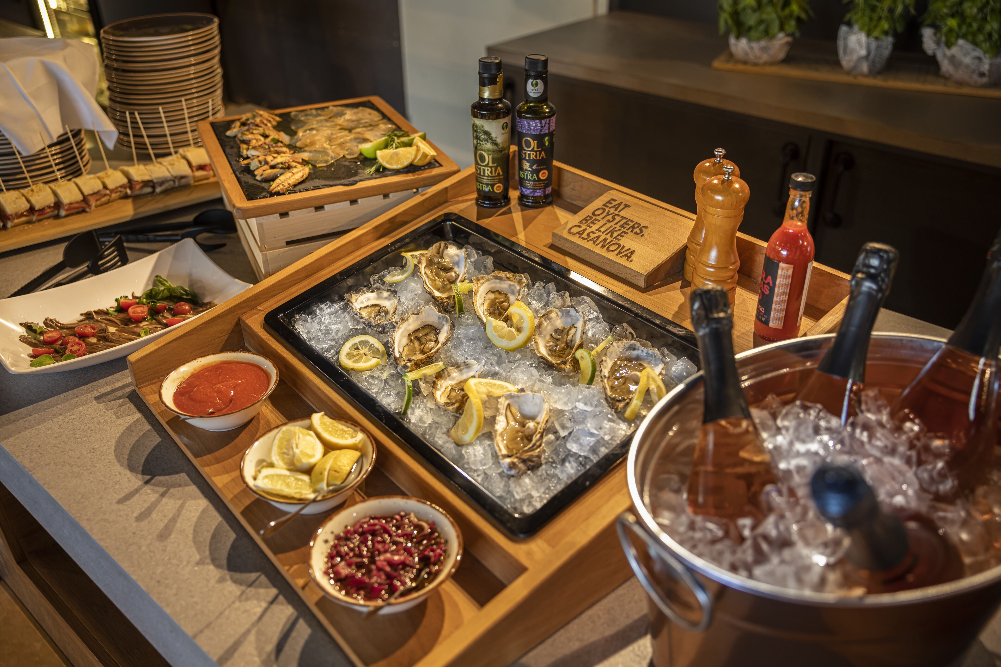 A buffet with seafood, including oysters on ice, and various condiments.
