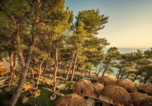 Un resort con mesas al aire libre, sombrillas de paja y vistas al mar.