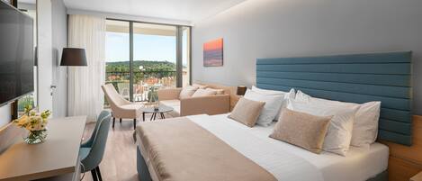 A modern hotel room with a large bed, a desk, and a balcony with a view.