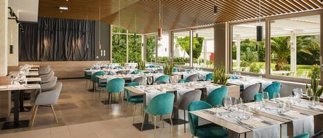 A modern restaurant with a wooden ceiling, large windows, and teal chairs.