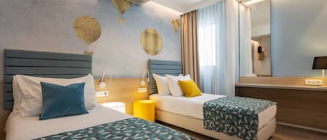 A hotel room with two beds, a large mirror, and a wall with hot air balloon decorations.