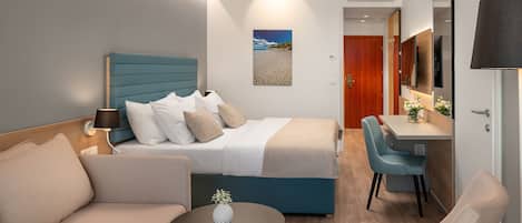 A modern hotel room with a bed, a desk, a chair, and a small table.