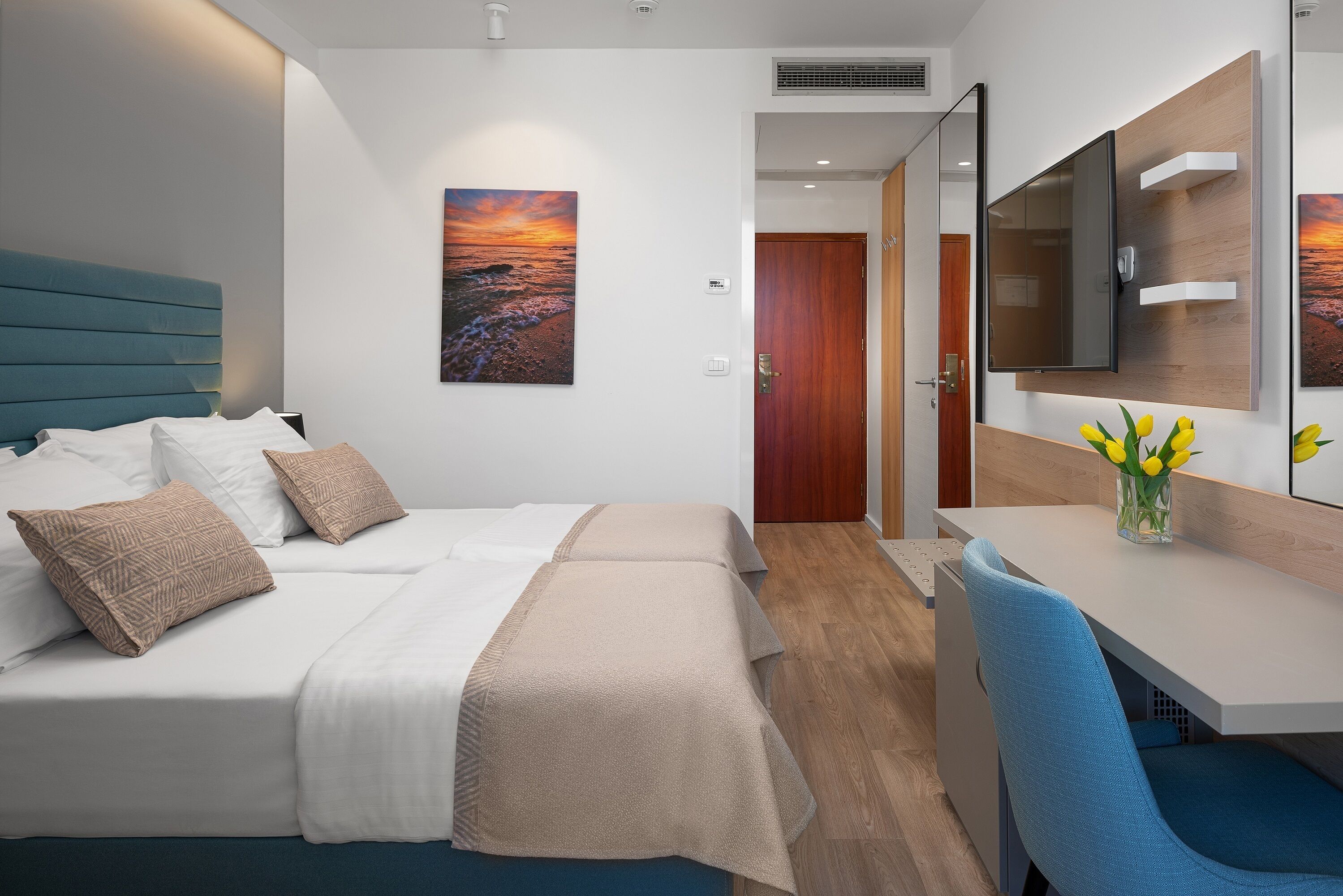 A hotel room with a bed, bedside table, and a desk with a chair.