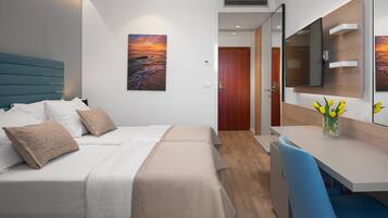 A hotel room with a bed, bedside table, and a desk with a chair.
