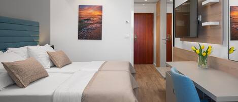 Une chambre d’hôtel avec un lit, une table de chevet et un bureau avec une chaise.