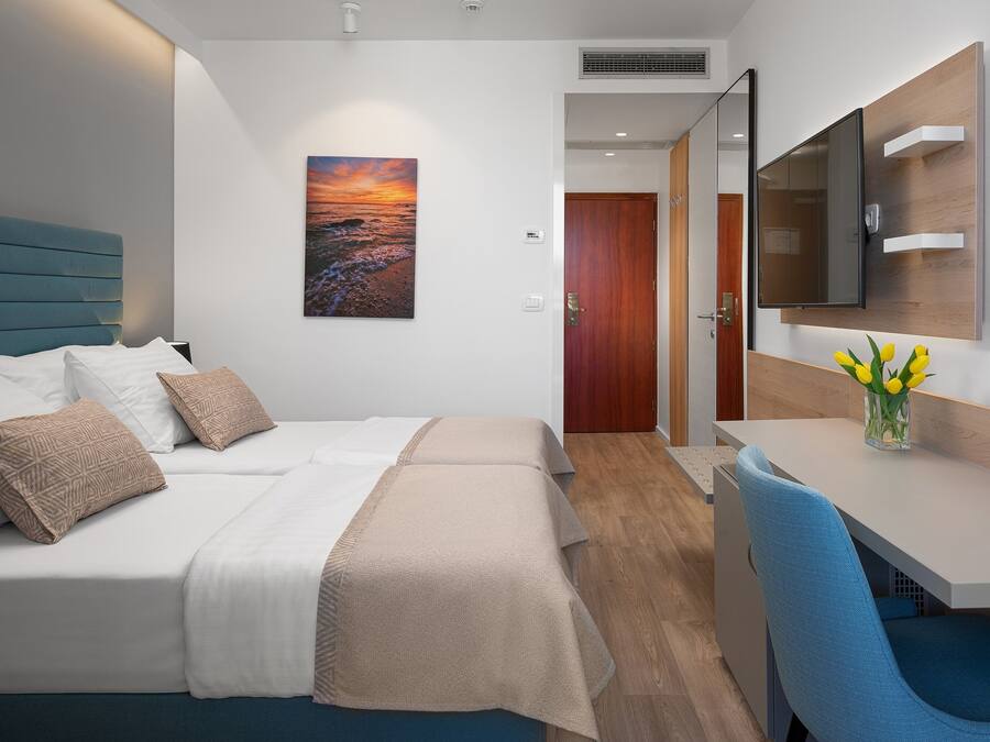 Una habitación de hotel con cama, mesita de noche y escritorio con silla.