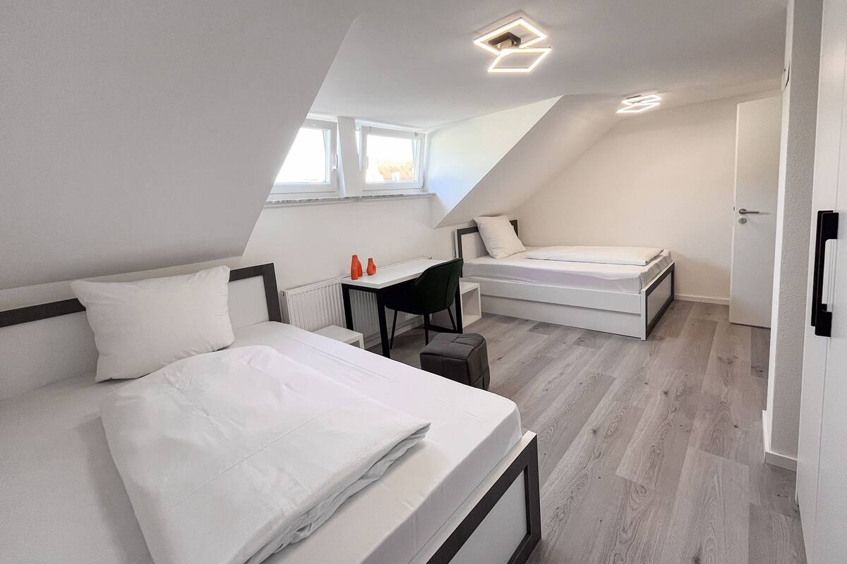 Una habitación moderna y funcional con dos camas, un escritorio y una silla.