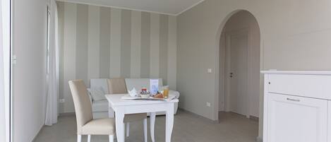 A dining area with a white table and chairs, a striped wall, and a ceiling light.