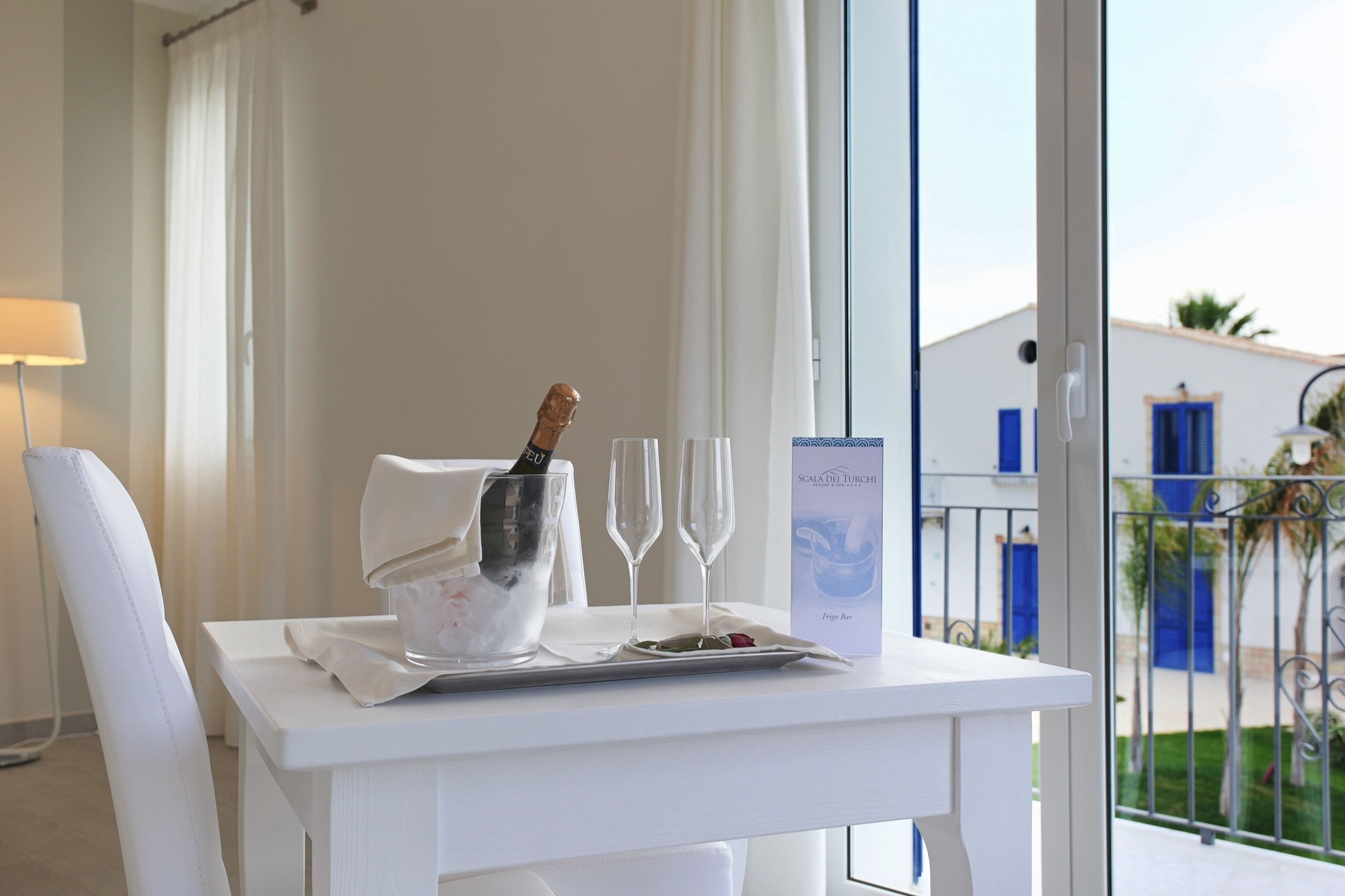 Ein weißer Tisch mit einer Champagnerflasche, zwei Gläsern und einer Speisekarte.