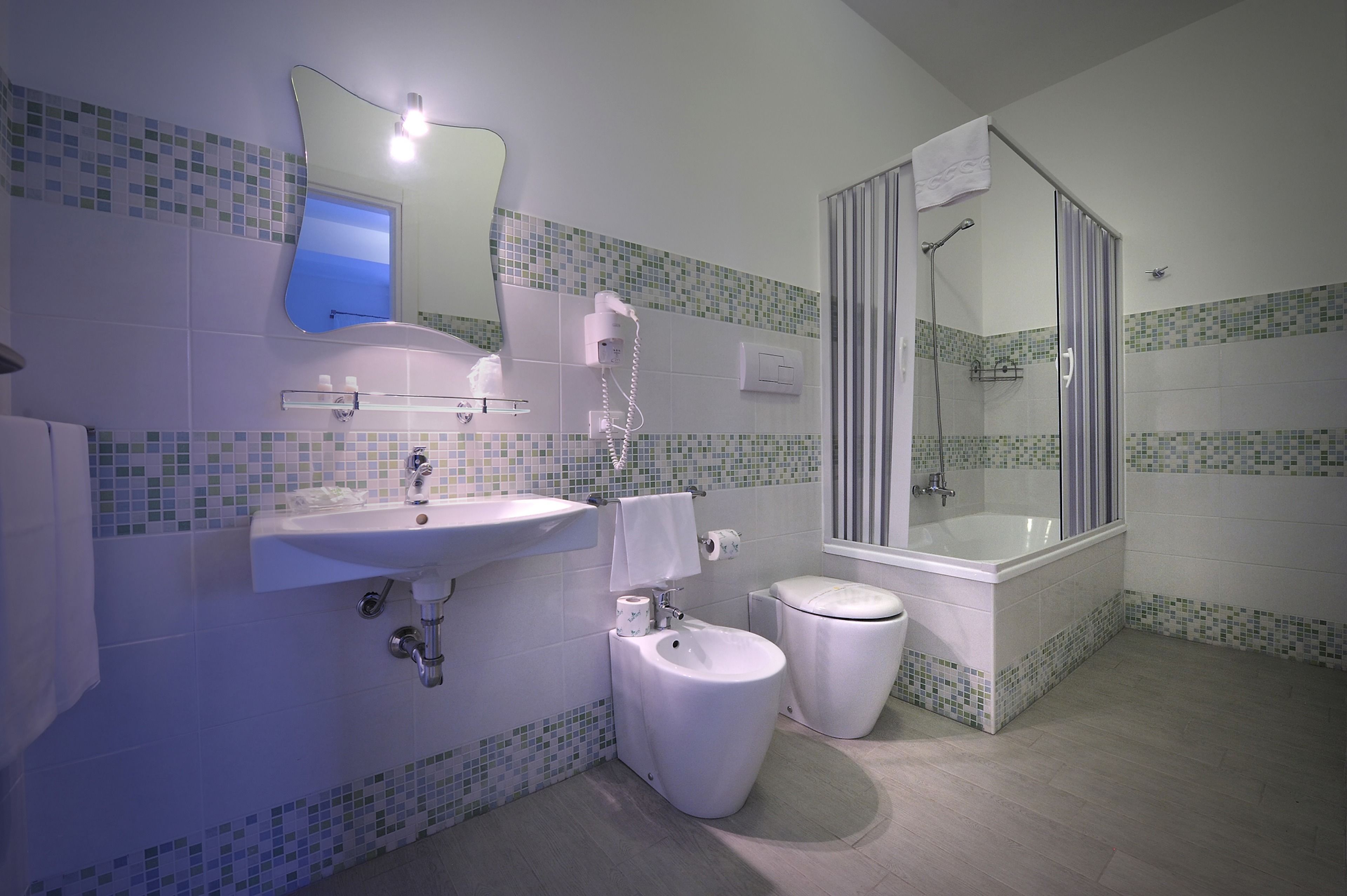A bathroom with a sink, toilet, bidet, and a glass-enclosed shower.