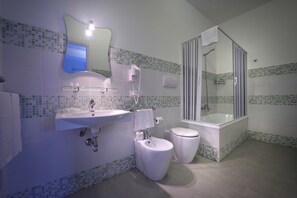 A bathroom with a sink, toilet, bidet, and a glass-enclosed shower. - Scala Dei Turchi Resort (Realmonte)