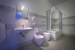 Un baño con lavamanos, inodoro, bidé y ducha con mampara de vidrio.