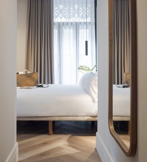 A hotel room with a bed, a bedside table, a lamp, a plant, and a window with curtains. - Room Mate Oliveira – City Centre, Valencia (Valencia)