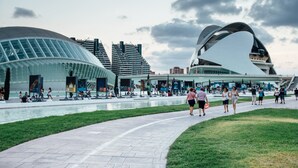 Un bâtiment d’architecture moderne doté d’une façade en verre incurvée et d’une vaste place agrémentée d’un élément aquatique.