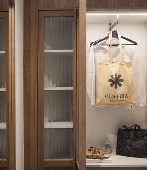 A wooden wardrobe with a mirrored door, a beige tote bag hanging on a hanger, and a black woven bag on a shelf. - Room Mate Oliveira – City Centre, Valencia (Valencia)