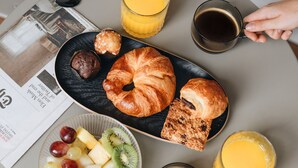 Une table de petit-déjeuner avec des croissants, des fruits et des boissons.