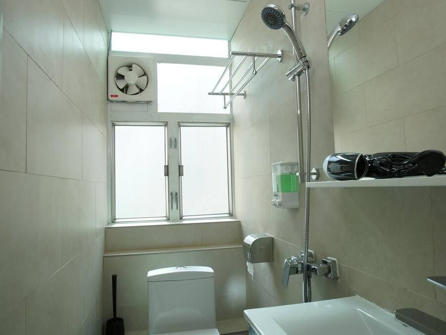 A small, modern bathroom with a toilet, a shower, a sink, and a window.