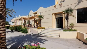 Ett hotell med en modern arkitektonisk design, med en central innergård med utomhusmöbler och palmer.