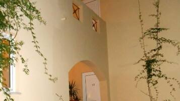 A staircase leading to a door marked with the number 12, surrounded by greenery and a large vase.