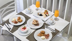 A breakfast table set with plates of food, including croissants, eggs, and pastries, along with two glasses of orange juice. - Club Zante Plaza (Zakynthos)