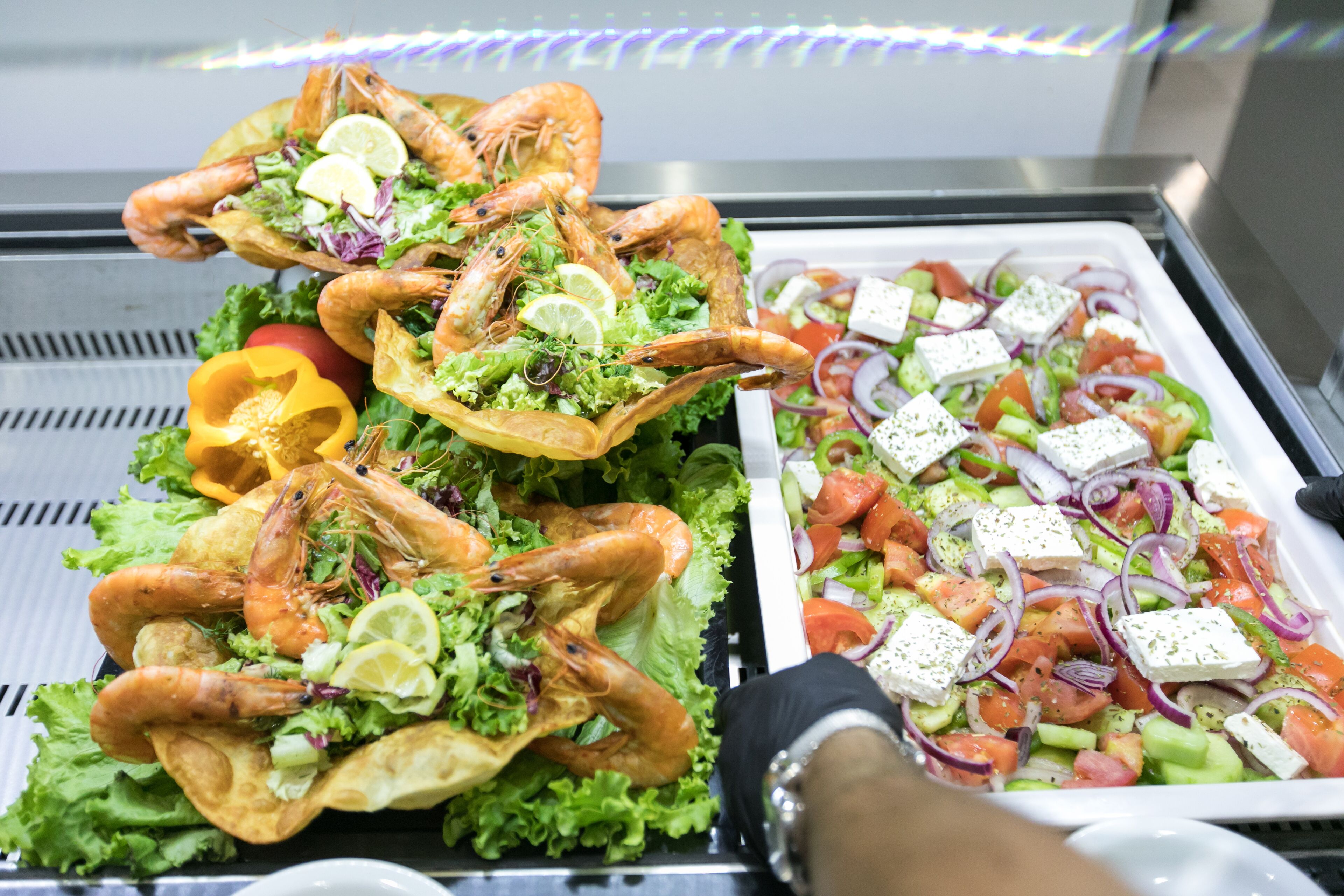 Un bufé con camarones, ensalada y queso feta.