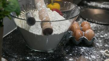 Un piano di lavoro della cucina con una ciotola piena di farina, un mattarello e delle uova.