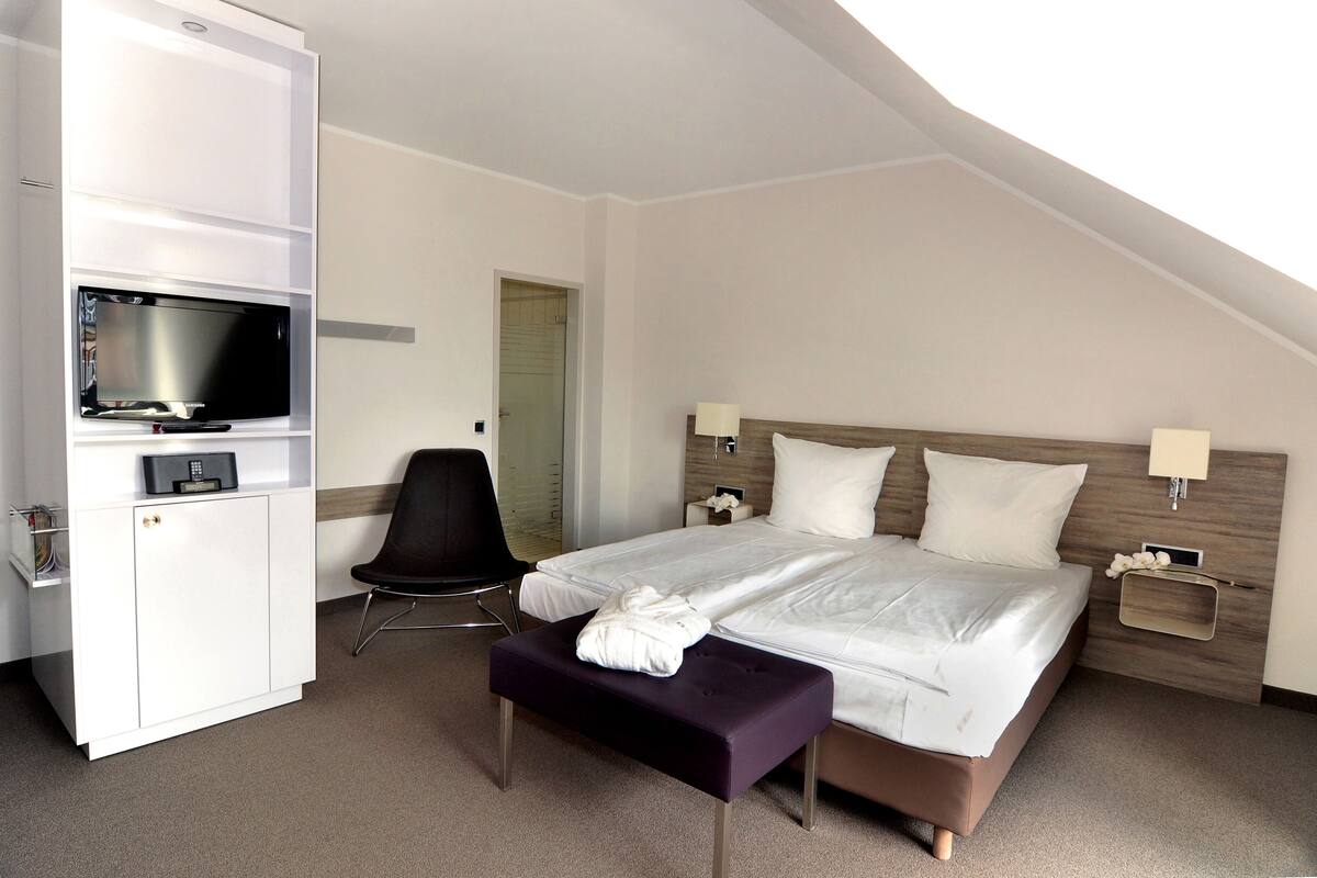 Ein Hotelzimmer mit Bett, Fernseher, Schreibtisch und Stuhl.