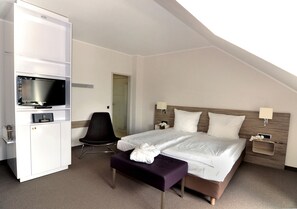 Ein Hotelzimmer mit Bett, Fernseher, Schreibtisch und Stuhl.