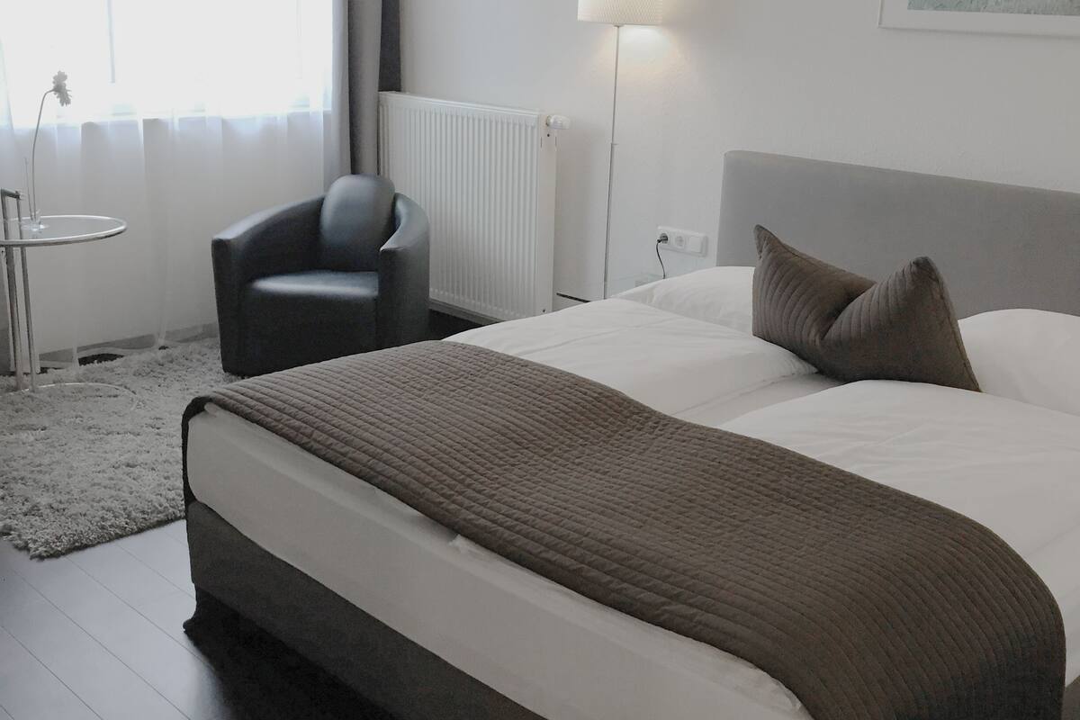 Ein Hotelzimmer mit Bett, Stuhl, Lampe und Heizkörper.