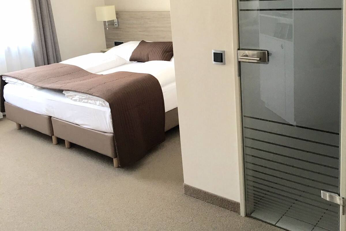 Ein Hotelzimmer mit einem Bett, einem Nachttisch, einer Lampe und einer Schiebetür.