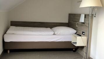 A bedroom with a bed, a bedside table, a lamp, and a painting on the wall.